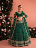 Woman wearing emerald embroidered net lehenga set with sheer dupatta and intricate bridal embroidery