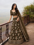 Woman wearing an olive green bridal lehenga with intricate embroidery, embellished hem and sheer dupatta