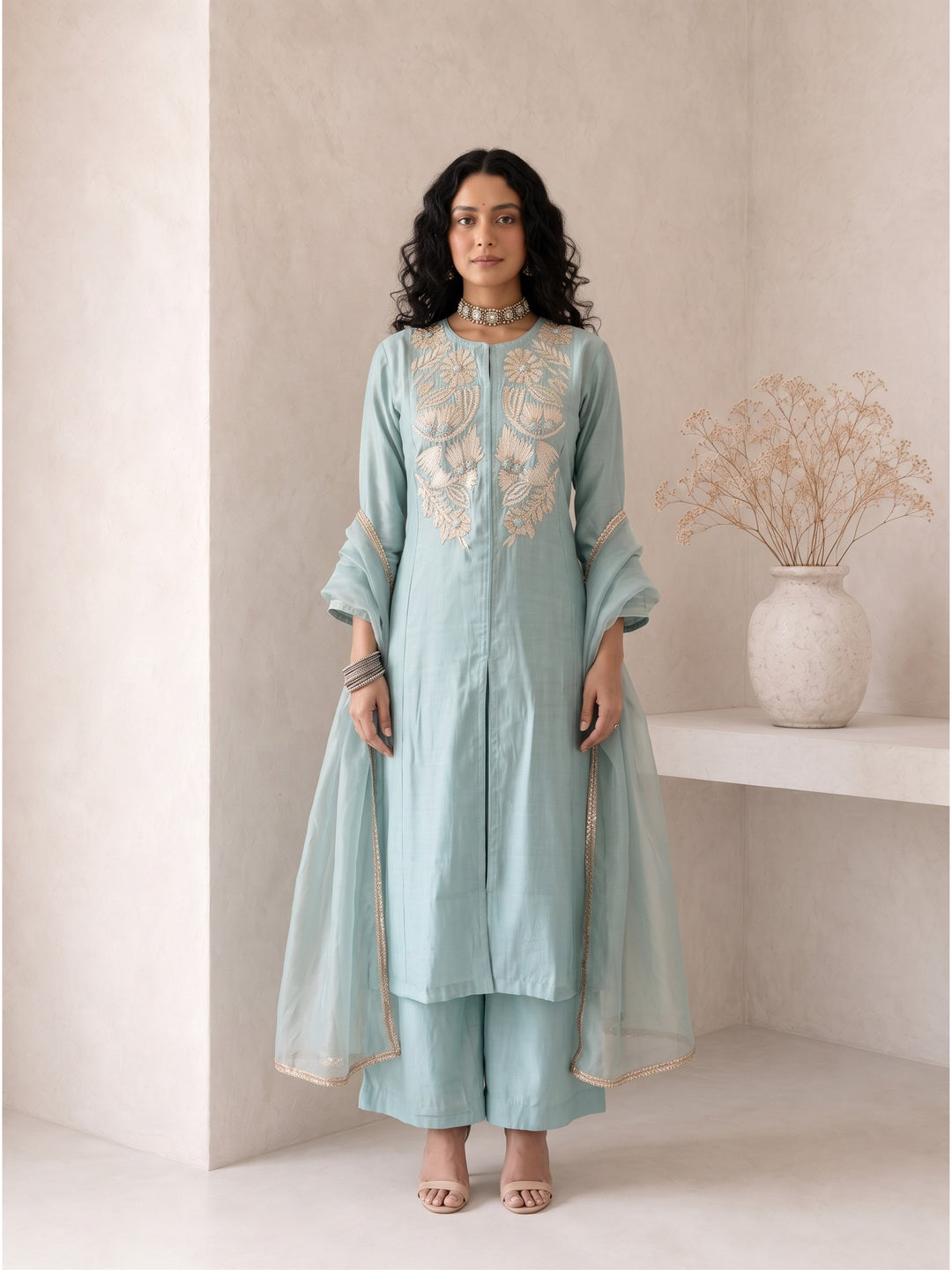 Model wearing Roselle Powder Blue Roman Silk Anarkali suit set with ivory floral embroidery, matching wide-leg pants and organza dupatta for Raksha Bandhan, weddings and festive occasions.