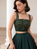 Close-up of the deep emerald green choli showing its square neckline, gold embellishment and shoulder straps