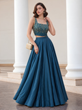 Teal blue lehenga set with gold-detailed choli and flared skirt, styled with a gold shoulder bag