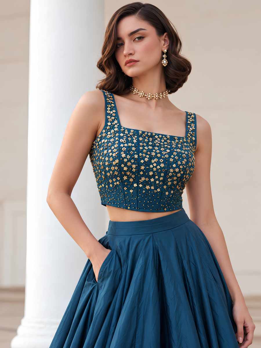 Close-up of the Midnight Noir teal blue choli showing its square neckline and intricate gold embellishments